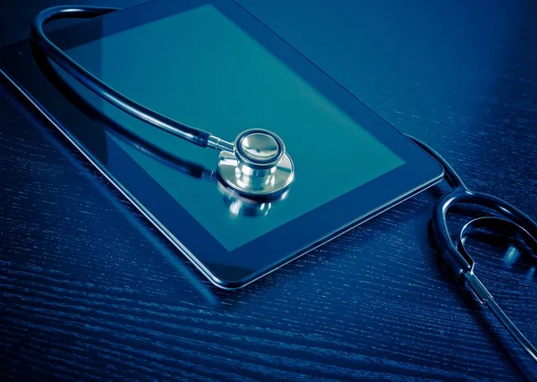 Medical stethoscope on modern digital tablet in laboratory on wood table