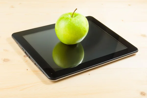 Green apple on digital tablet pc on wood table