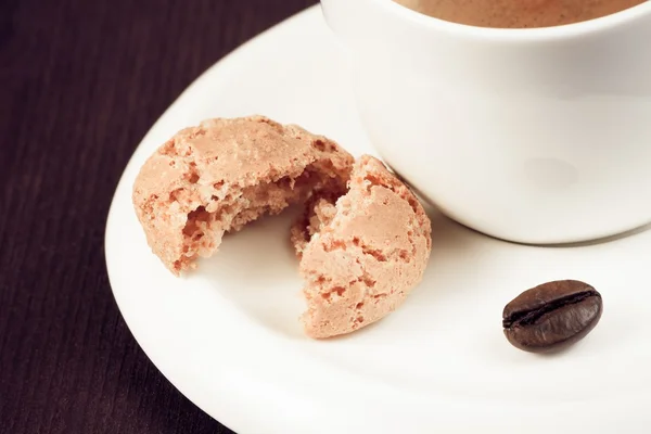 Close-up of cup of italian espresso coffee and biscuit near coffee bean