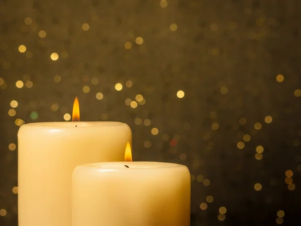Candles with flame on golden bokeh
