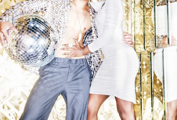 70s disco style couple posing with mirror ball