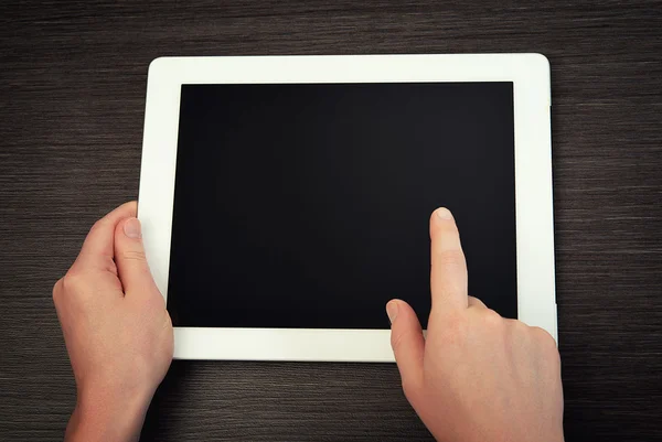 White tablet with a blank screen in the hands on table