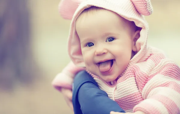 Happy smiling baby girl in pink hood with ears