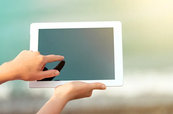 White tablet with a blank screen in the hands