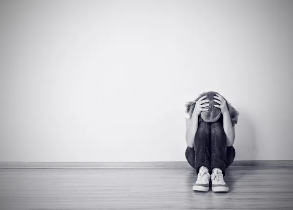 Girl sits in a depression on the floor near the wall