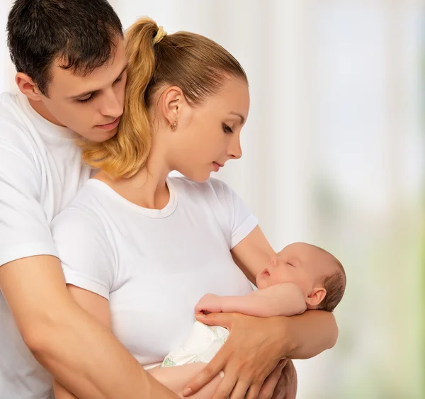 Happy young family of mother, father and newborn baby in their a