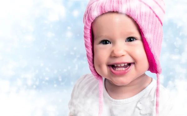 Happy baby girl in winter hat smiling on outdoors