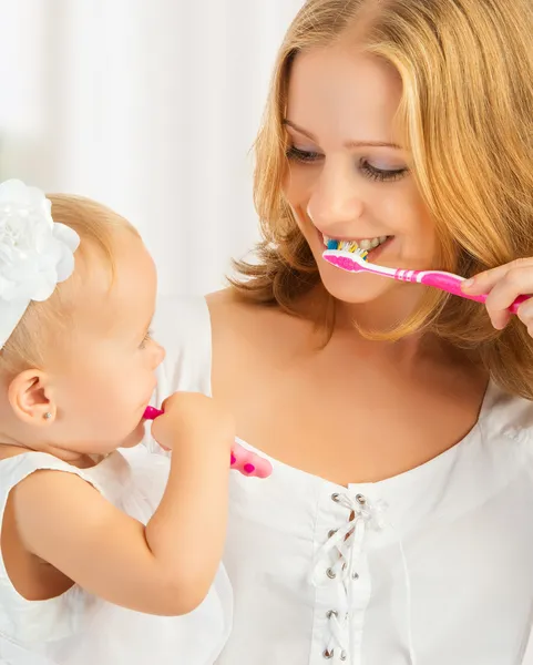 Mother and daughter baby girl brushing their teeth together