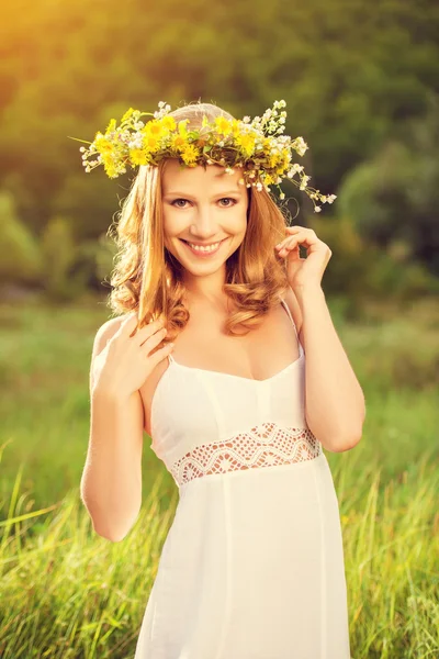 Beautiful woman in wreath of flowers lies in the green grass out