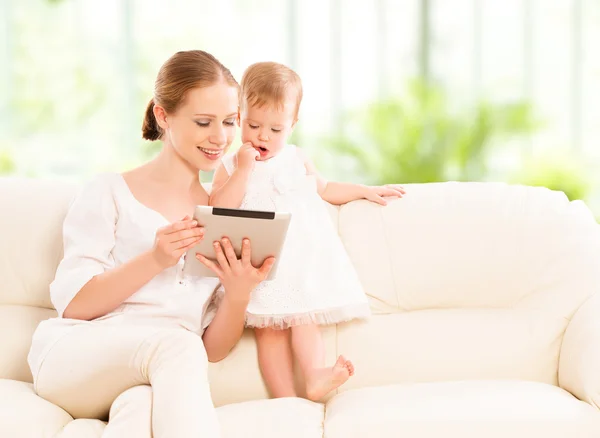 Mother and baby child with tablet computer on the couch at home
