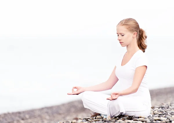Woman meditating in  lotus yoga on beach