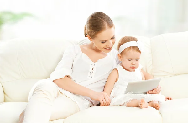Mother and baby child with tablet computer on the couch at home
