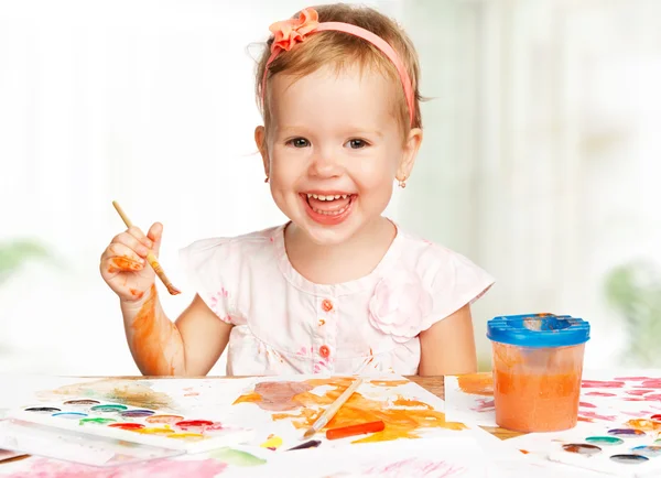 Happy child girl draws paints