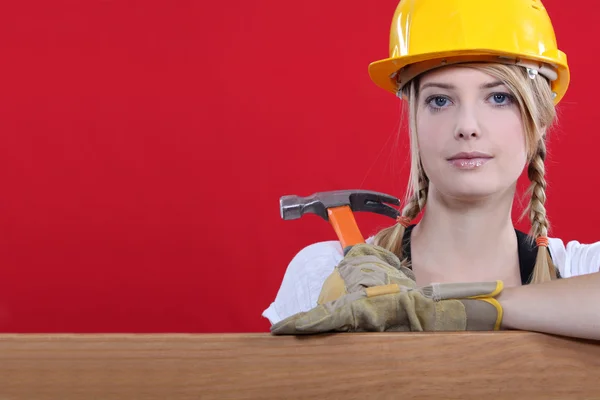 Woman resting on wooden beam with hammer