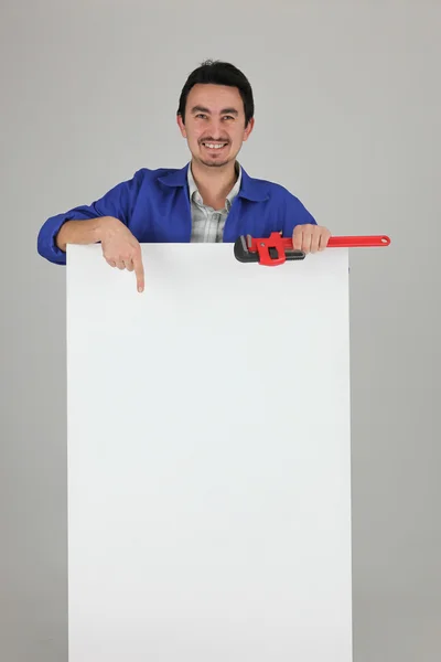 Man with a wrench pointing at a board left blank for your image