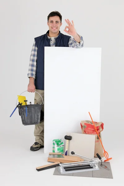 Craftsman posing behind an ad board and making an okay sign