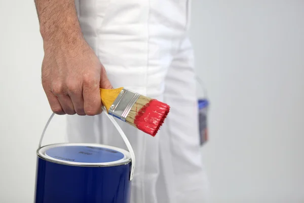 Decorator holding paint and paint brush