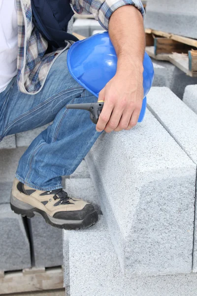 Construction worker kneeling by concrete blocks