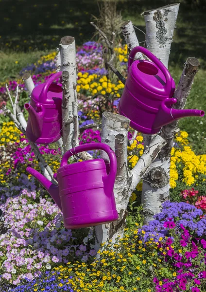 Colorful flower garden with watering can hanging down