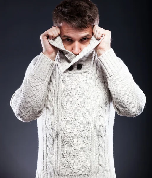 Young man in white sweater shivering from cold