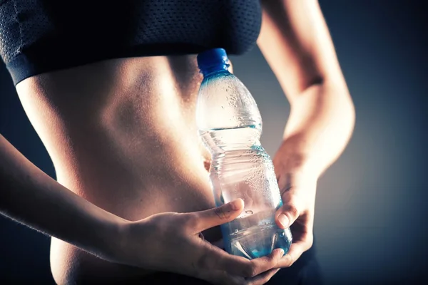 Sweaty woman after training holding water bottle
