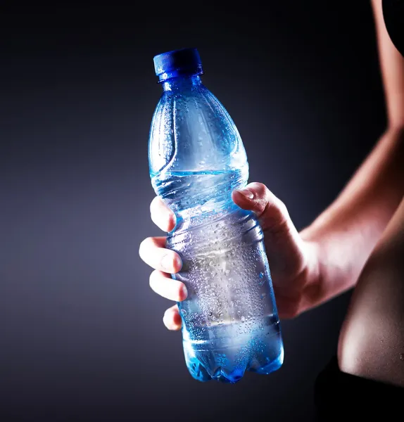 Water bottle in fitness woman hand, concept of health