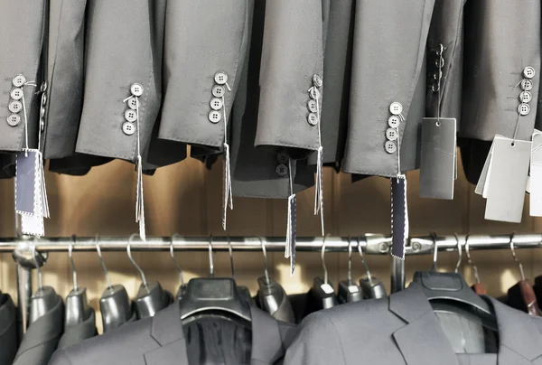 Row of elegant suits jacket on hangers, apparel store