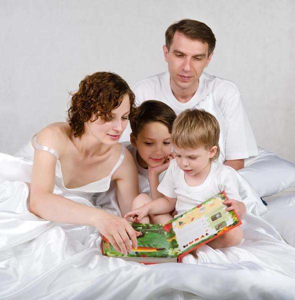 Parents with children read book in the bed — Stock Photo #12329499