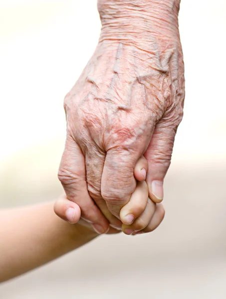 A small kid holding hands of an old woman