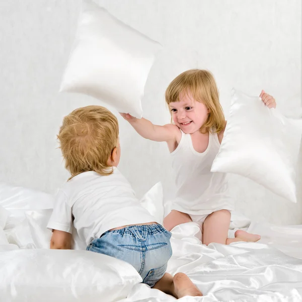 Portrait kids fighting with pillows in bed - Indoor