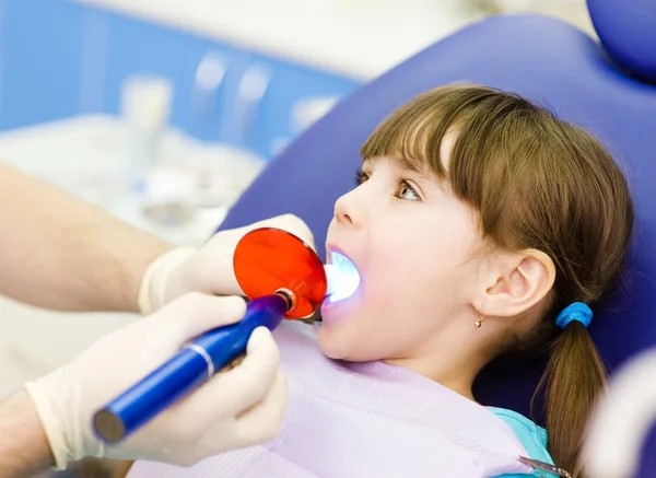 Little girl with open mouth receiving dental filling drying procedure