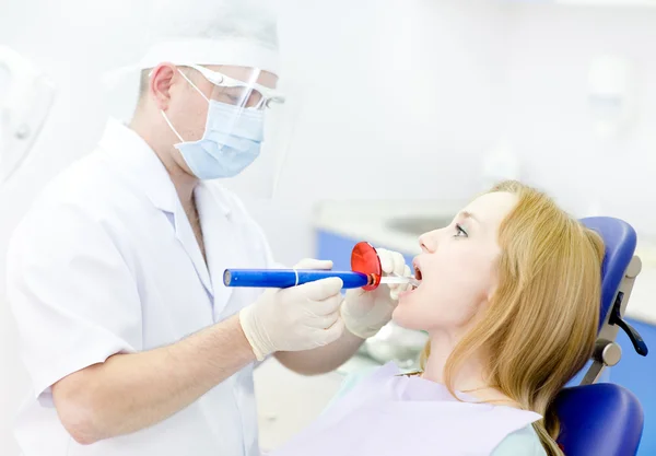 Young woman with open mouth receiving dental filling drying procedure