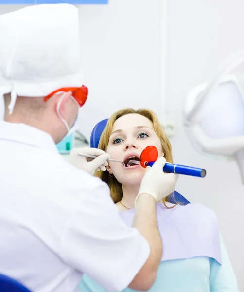 Woman with open mouth receiving dental filling drying procedure.