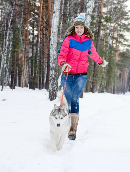 Woman running with dog in winter forest