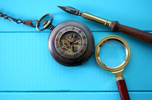 Antique pocket watch with a magnifying glass and an old pen