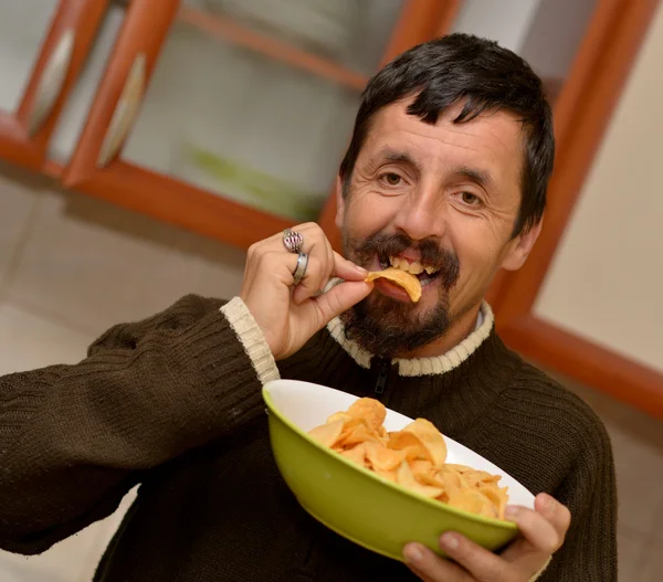 Portrait of young brunette man eating chips