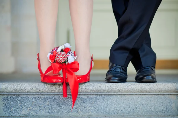 Red shoes and a Bride's bouquet and black shoes groom close-up
