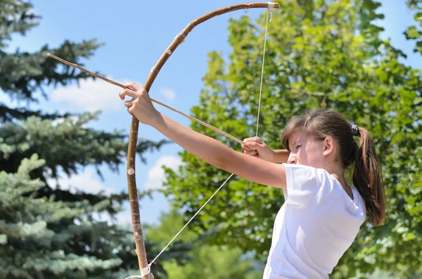 Teenage girl taking aim with a bow and arrow