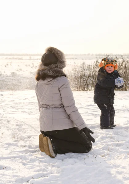 Small boy throwing a snowball at his mother