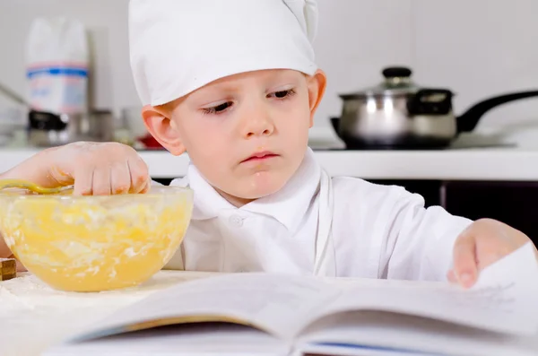 Little boy following a recipe as he bakes a cake