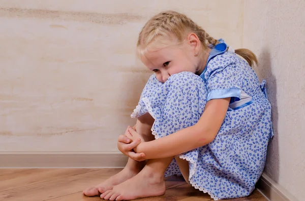 Sad young girl sitting in corner