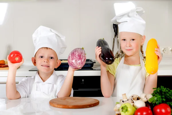 Two smiling children holding up fresh vegetables
