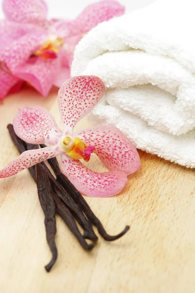 Vanilla beans, white towel and orchid flower