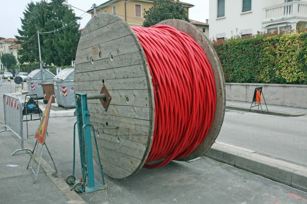 Coils of red high-voltage power cable in middle of road