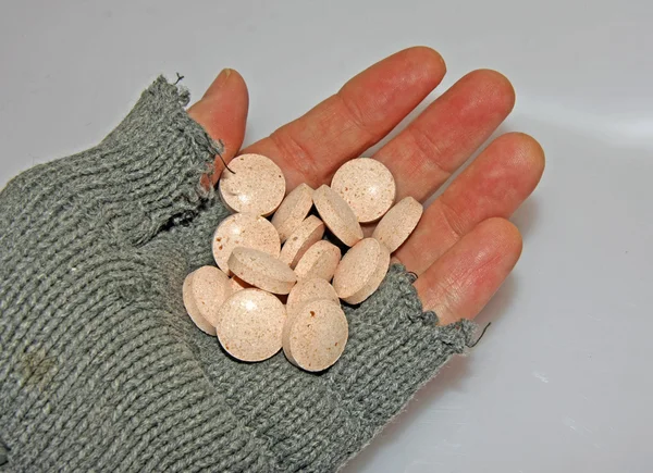 Hand of poor man holding a handful of medicines