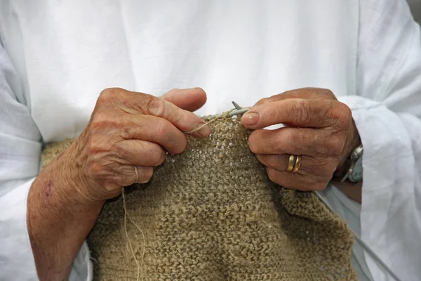 Hands of an elderly woman during the processing of wool sweater
