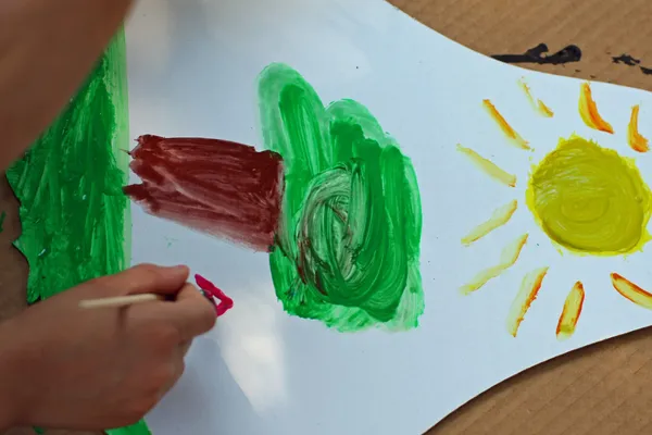 Child draws a tree at school during the drawing lesson