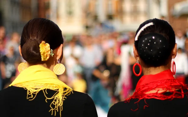 Heads of two women with very hairstyle and a yellow and red scar