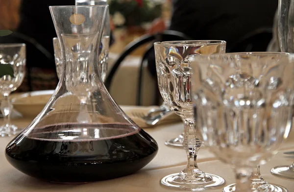 Carafe decanter with red wine in a table with many glass