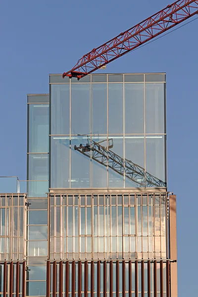 Crane with mirror glass skyscraper under construction